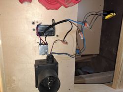 Zbliżenie na instalację elektryczną z otwartym gniazdem i odkrytymi przewodami na drewnianej powierzchni.