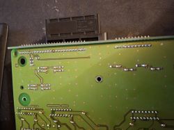 Zbliżenie na zieloną płytkę PCB z lutami i ścieżkami, z czarnym złączem u góry