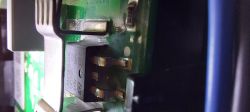 Zbliżenie na komponent elektroniczny na płytce drukowanej z widocznymi pinami i oznaczeniami.