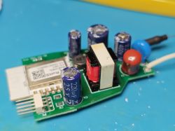 Zbliżenie płytki PCB z kondensatorami, transformatorem i ekranowanym modułem radiowym na niebieskiej macie