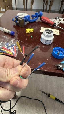 Person holding a set of wires with colorful insulation against a table with electrical tools.