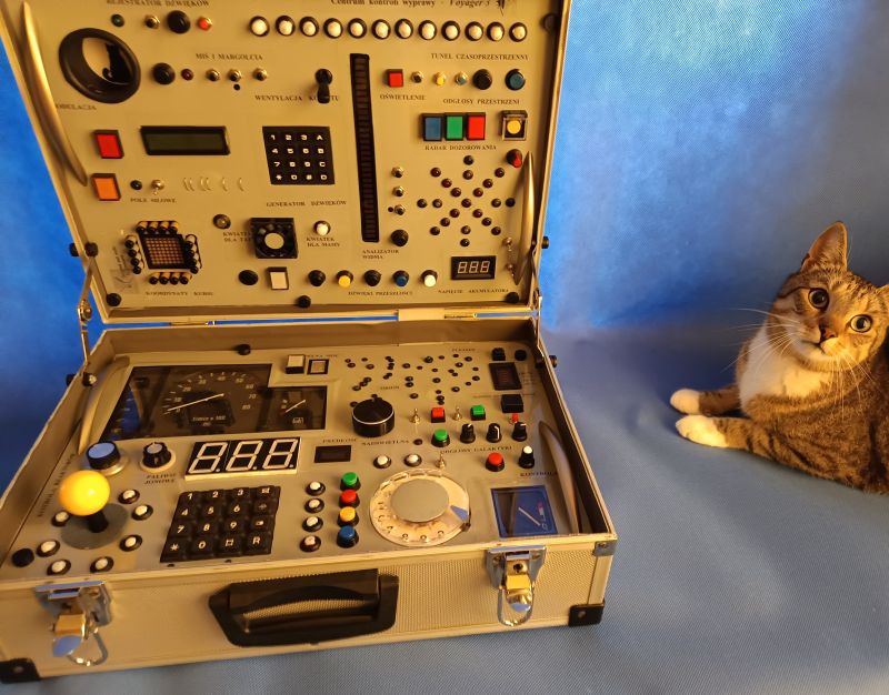Voyager 3 Mission Control Center Toy Panel and Cat A suitcase with a complex child’s control panel toy styled as a mission command center, with a cat sitting next to it.
