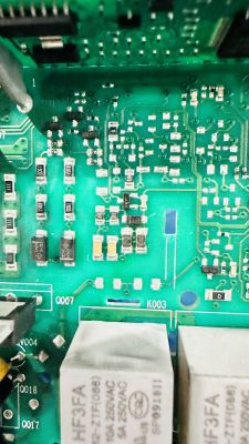Zbliżenie na płytkę drukowaną z widocznymi elementami elektronicznymi i kodami.