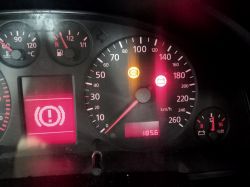 Zbliżenie na desce rozdzielczej samochodu z widocznymi wskaźnikami i kontrolkami.