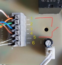 Zbliżenie płytki PCB ze złączem i opisami pinów 1–6, m.in. 12V i LOCK, zaznaczone czerwonym obrysem