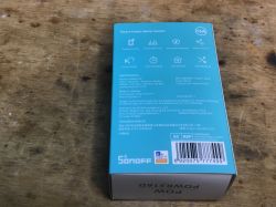 Sonoff POWR316D energy meter packaging on a wooden surface.