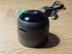 Rotating surveillance camera on a table Black rotating camera on wooden table with ports visible and cable in background