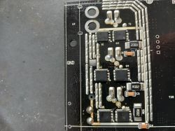 Zbliżenie na płytkę PCB ze sterownika hulajnogi z widocznymi sześcioma tranzystorami SMD i rezystorami oznaczonymi R002.