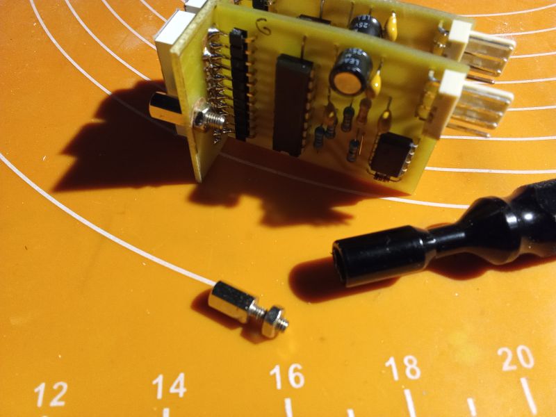 Electronic circuit board on an orange mat with small components.