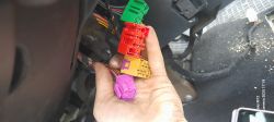 Kolorowe kostki elektryczne (zielona, czerwona, żółta, fioletowa) pod kolumną kierowniczą Volkswagena Golfa IV z 2001 roku, trzymane w ręce.