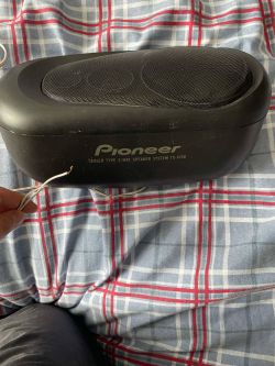 Głośnik Pioneer TS-X150 z dwoma wystającymi kablami na tle wzorzystej pościeli.