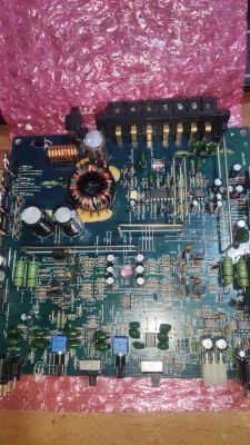 Płyta drukowana wzmacniacza z komponentami elektronicznymi na różowym tle.
