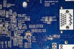 Zbliżenie na niebieską płytę drukowaną z różnorodnymi elementami elektronicznymi i oznaczeniami.