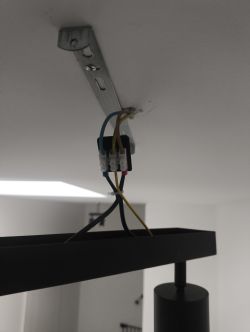 Połączenie elektryczne lampy sufitowej z widocznymi trzema przewodami i złączką