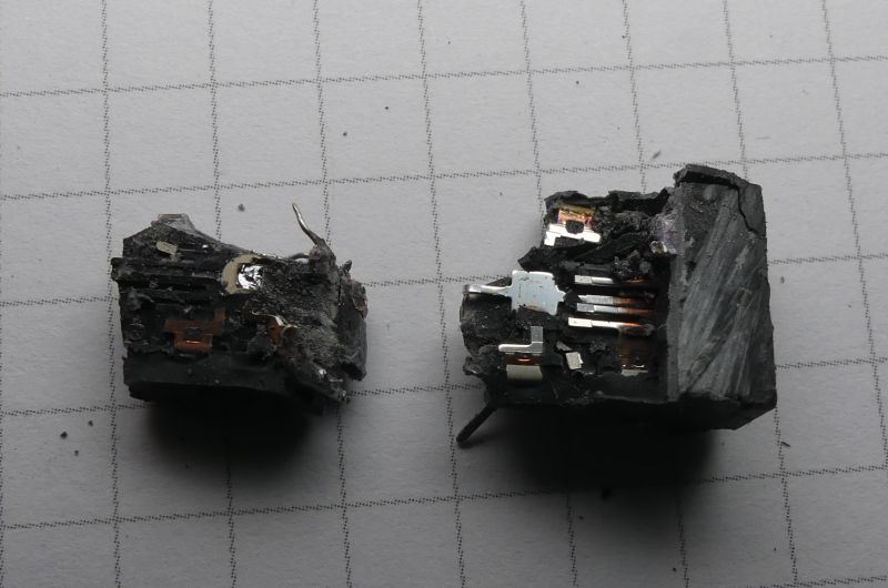 Dwa spalone fragmenty elektronicznego komponentu na tle w kratkę