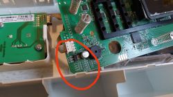 Zdjęcie wnętrza urządzenia elektronicznego z widoczną płytką drukowaną, na której element zaznaczono czerwoną elipsą.