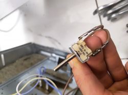 Osoba trzyma element elektroniczny piekarnika oznaczony 2/1P 16A 250V 48-19 T300.
