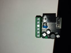 Close-up of a circuit board with a green screw terminal block and a black relay