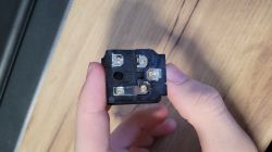 Złącze IEC 3-pin widziane od strony lutowania, widoczne styki i metalowa płytka L