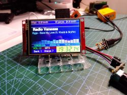 LCD module on a red PCB shows “Radio Vanessa” and MP3 playback on a cutting mat