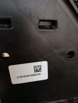Czarny plastikowy element z białą naklejką zawierającą kod numeryczny i kod QR.