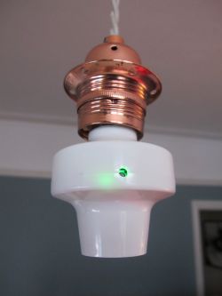 Light Bulb Socket with Adapter and Green LED Close-up of a copper light bulb socket with a white adapter featuring a glowing green LED.