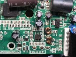 Zbliżenie na płytkę drukowaną z elementami elektronicznymi, w tym kondensatorami i regulatorami napięcia.