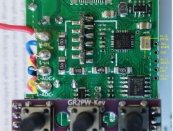 Close-up of a printed circuit board with electronic components, including chips, resistors, and labeled pins.