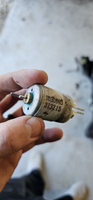 Person holding a small electric motor with markings 103088 and 913215.