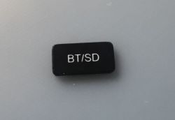 Small black rectangular button labeled “BT/SD” on a light gray surface
