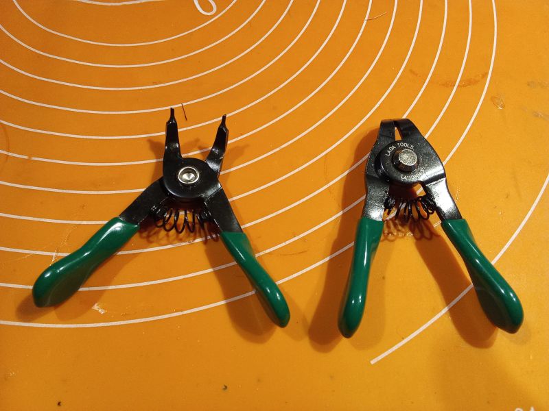 Dwa narzędzia z zielonymi uchwytami na pomarańczowym tle