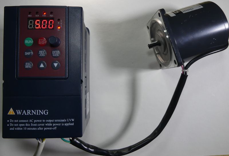 Falownik z podłączonym silnikiem elektrycznym na białym tle.