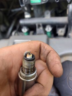 Iskra świecy zapłonowej trzymana w ręce nad komorą silnika.