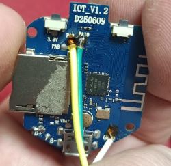 Round PCB with micro‑USB port, card slot, and soldered wires, held between fingers