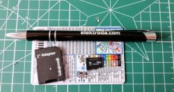 A pen, card adapter, and memory card on a printed chart against a green cutting mat.