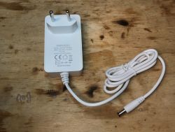 White Power Supply Model JKY0918-1201500E White power supply model JKY0918-1201500E with a cable on a wooden background.