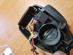 Wnętrze obudowy z widocznymi kolorowymi przewodami połączonymi z małą płytką drukowaną.