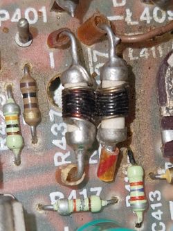 Element elektroniczny z ciemnym zwojem drutu na płytce drukowanej.