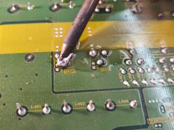 Proces wylutowywania tranzystora z płytki PCB przy użyciu lutownicy.