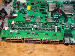 Płyta główna starego switcha sieciowego z widocznymi portami Ethernet oraz częściowo zdemontowanymi modułami elektronicznymi.