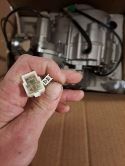 Wtyczki elektryczne w dłoni na tle nowego silnika motorowerowego.