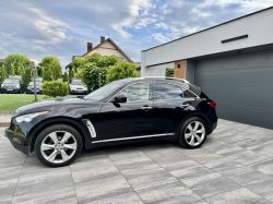 Black Infiniti FX SUV parked on a tiled driveway next to a modern house