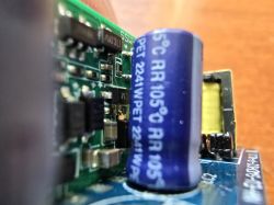 Close-up of an electronic component on a circuit board, including a blue electrolytic capacitor.