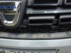 Zbliżenie na przedni grill Dacii z odbarwieniem i smugami na zderzaku