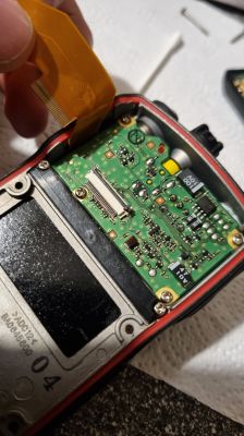 Zbliżenie na wnętrze radia Yaesu VX-6R z widoczną płytką drukowaną i taśmą połączeniową