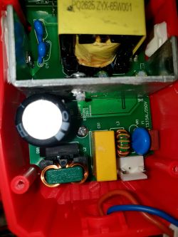 Wnętrze prostownika z widocznymi podzespołami elektronicznymi, cewkami i kondensatorami