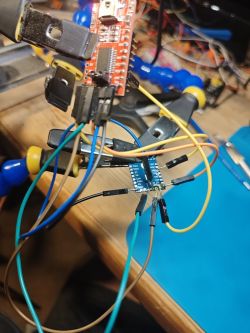 Circuit board connected to a programmer with wires on a desk.