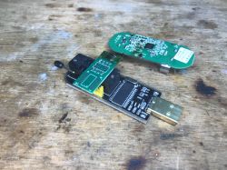 Sonoff DW2-WiFi Sensor and USB Programmer on a Surface Sonoff DW2-WiFi sensor PCB and USB programmer on a wooden surface.