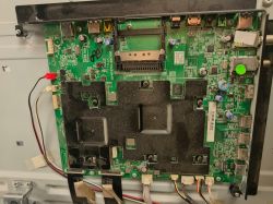 Płyta główna telewizora z czarnymi radiatorami oraz portami HDMI i USB na krawędzi.