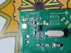 Zbliżenie na płytkę drukowaną z elementami elektronicznymi i oznaczeniami.